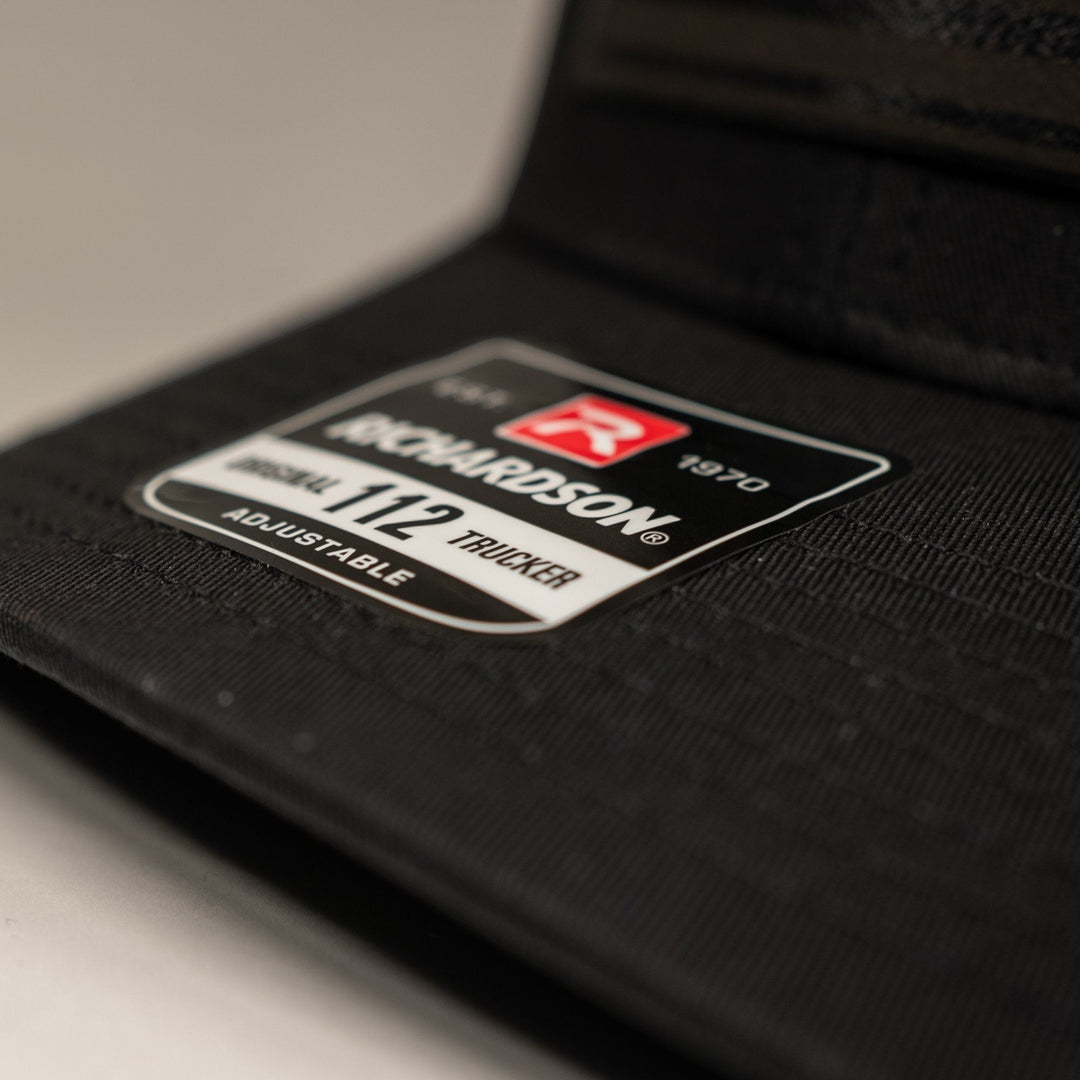 Single Track Hats black trucker cap with a black leatherette USA flag patch. Adjustable snapback.